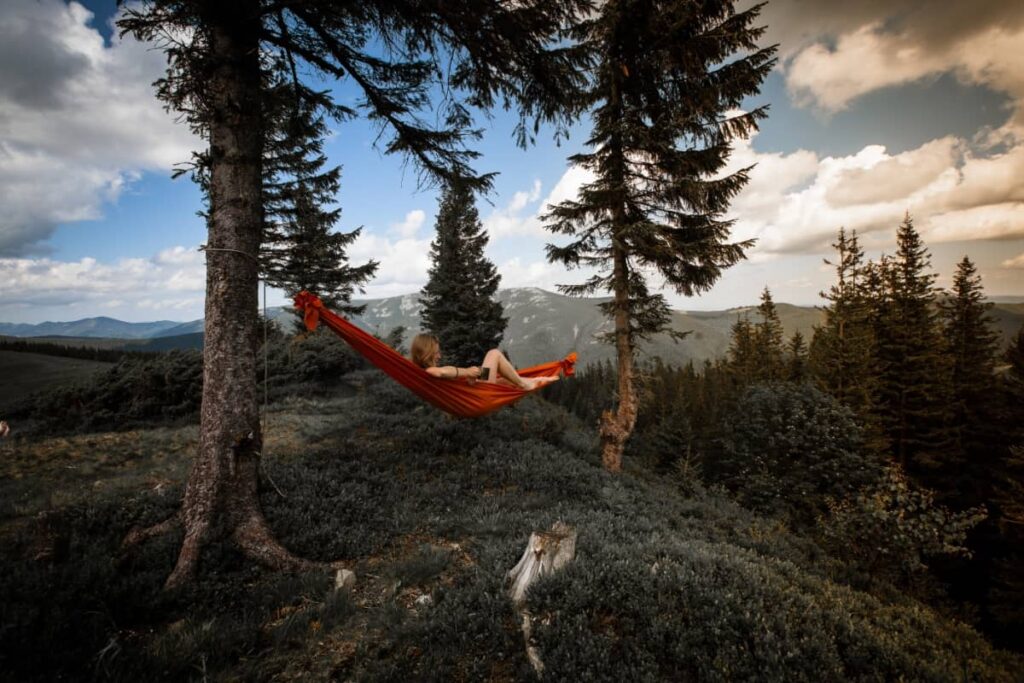 photo of a woman drinking coffee in a camping hammock