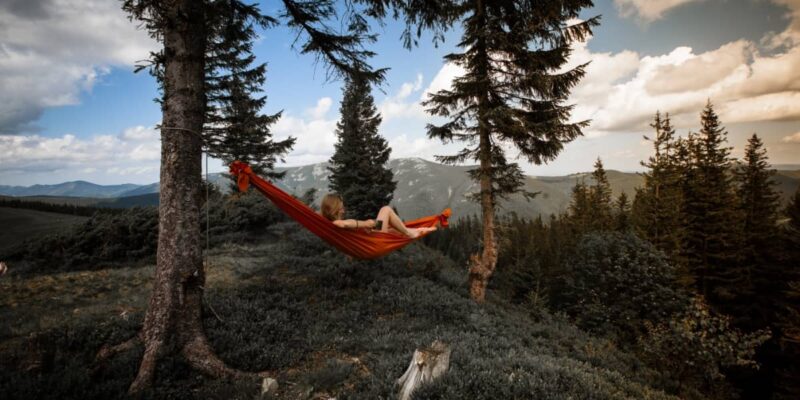 photo of a woman drinking coffee in a camping hammock